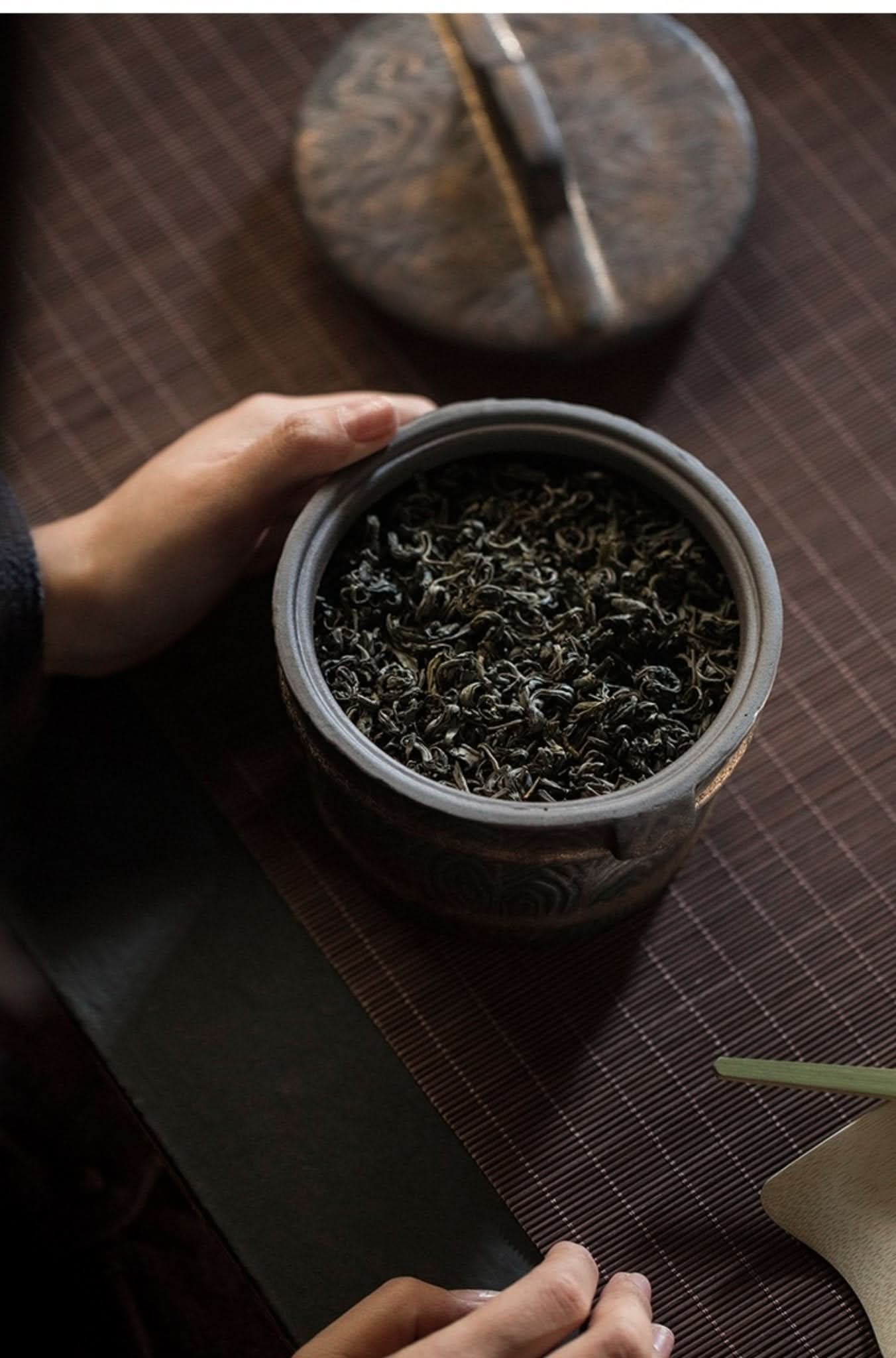 Pottery Japanese tea jar filled with loose leaf tea, vintage tea can with ornate details.